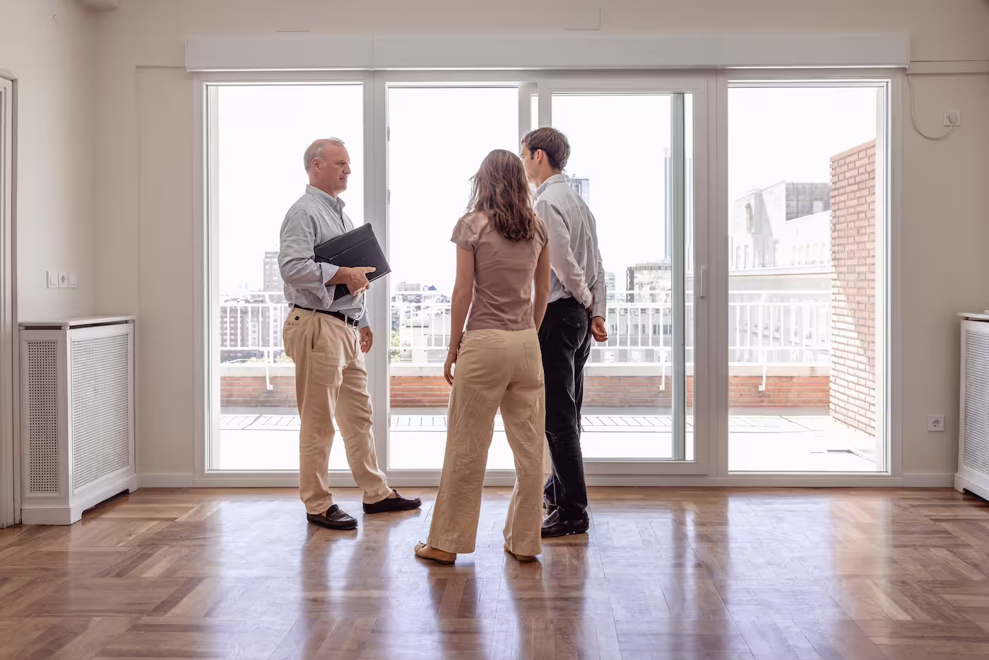 Symbolisches Bild eines Immobilienmaklers, der gleichzeitig auch HYPOFY-Tippgeber sein kann bei einer Wohnungsbesichtigung mit einem interessierten Paar.